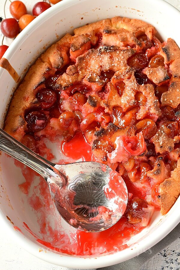 birdseye view of a white baking dish with scooped out cherry cobbler