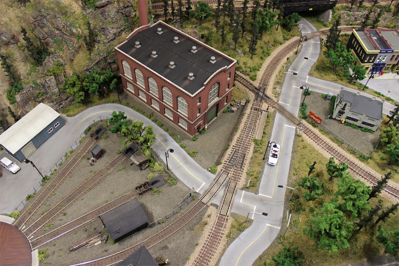 Areal view of a plaster road crossing a track turnout and leading into an industrial and railyard area