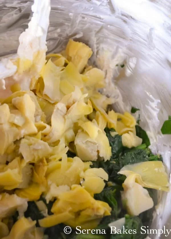 Mixing bowl with artichoke hearts and Spinach in mixing bowl.