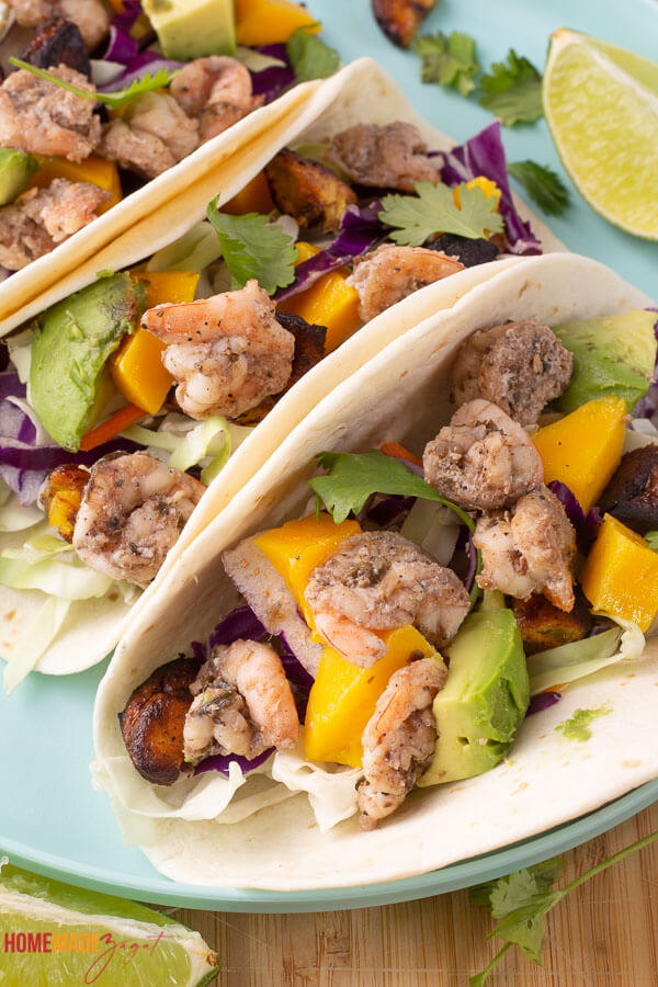 The BEST homemade jerk shrimp taco recipe you can find. Spicy shrimp layers on crunchy cabbage slaw and topped with avocado, mango and plantains.