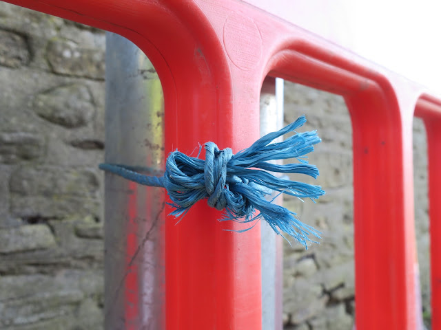Blue nylon twine tying red barrier to new lampost.