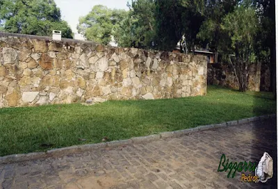 Construção do muro de pedra rústica com o gramado com grama São Carlos, o calçamento com pedra paralelepípedo e as guias de pedra folheta.