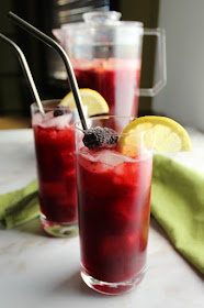 The perfect combination of tart, bright and lightly sweet, this homemade blackberry lemonade is sure to become your favorite warm weather drink. two glasses of homemade blackberry lemonade with pitcher of blackberry lemonade in the background