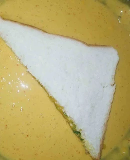 Dipping triangular shape bread pakora into the batter