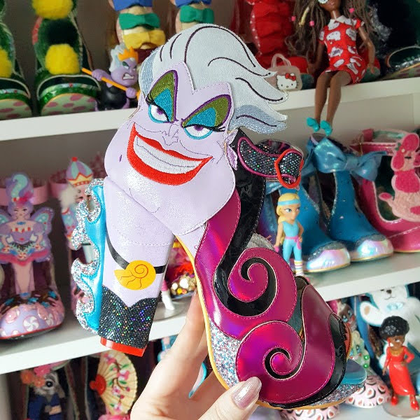 Irregular Choice Elegant Evil shoe in hand with shoe shelves in background