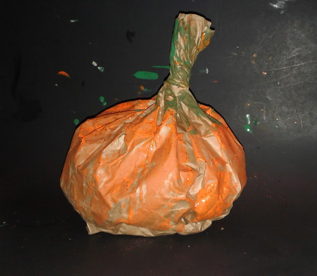 Directions to make a simple Halloween or autumn pumpkin decoration out of a brown lunch bag, shredded paper, glitter and paint.  Toddler friendly.