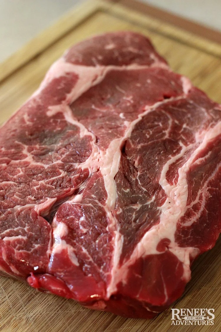 Raw chuck roast on a wooden cutting board ready for Dutch Oven Pot Roast by Renee's Kitchen Adventures