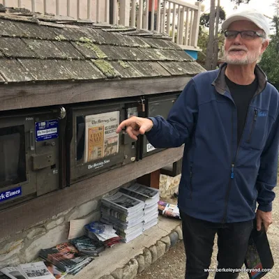 Carmel Walks guide Kelly Steele in front of rustic newstand in Carmel, California
