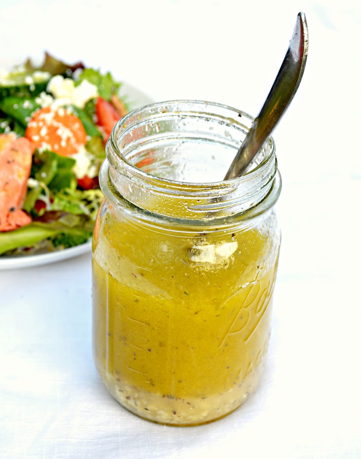 Lemon Vinaigrette Recipe in a mason jar glass with a salad in the background.
