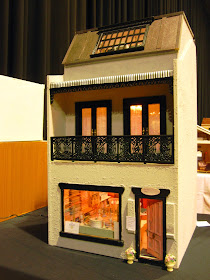 Front view of a three-storey modern miniature shop building.