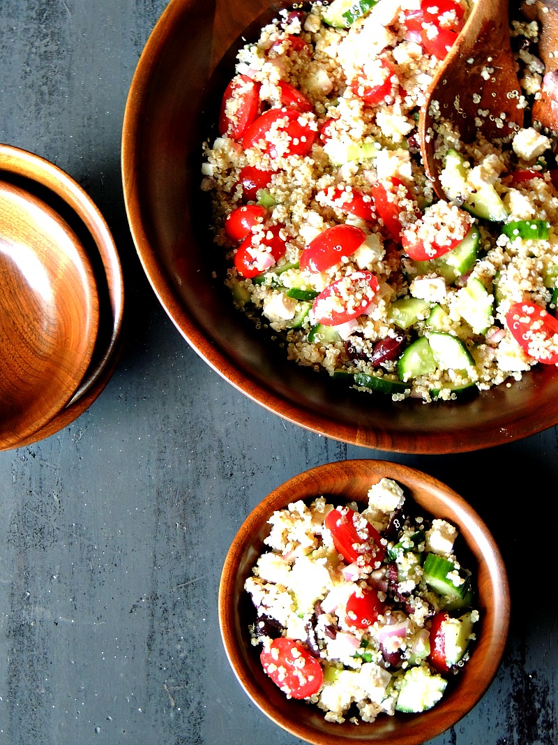 Mediterranean Quinoa Salad in a wooden salad bowl on a blue table.