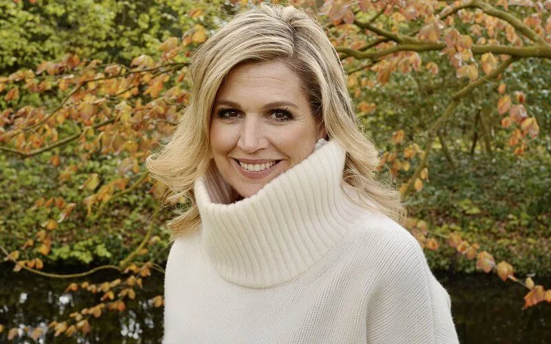 Queen Maxima wore a houndstooth cape by Saint Laurent, and white high neck sweater pullover by Zara, H&M, and floral earrings by Zara