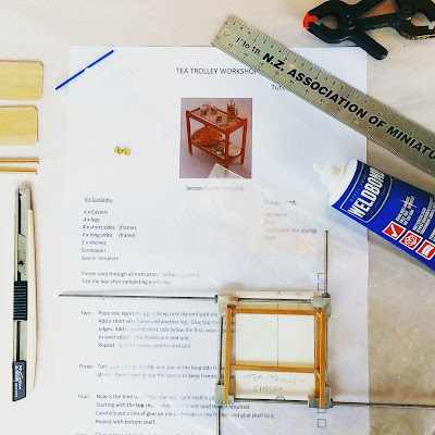 Components of a one-twelfth scale tea trolley kit laid out on the instruction sheet. Around the edges are the tools needed for the project.