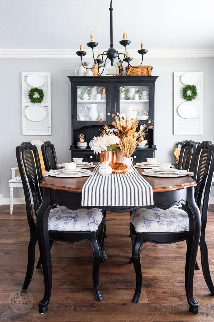dining room with vintage black chairs and hutch, blue toile seats, shutters, white ironstone and warm fall colors