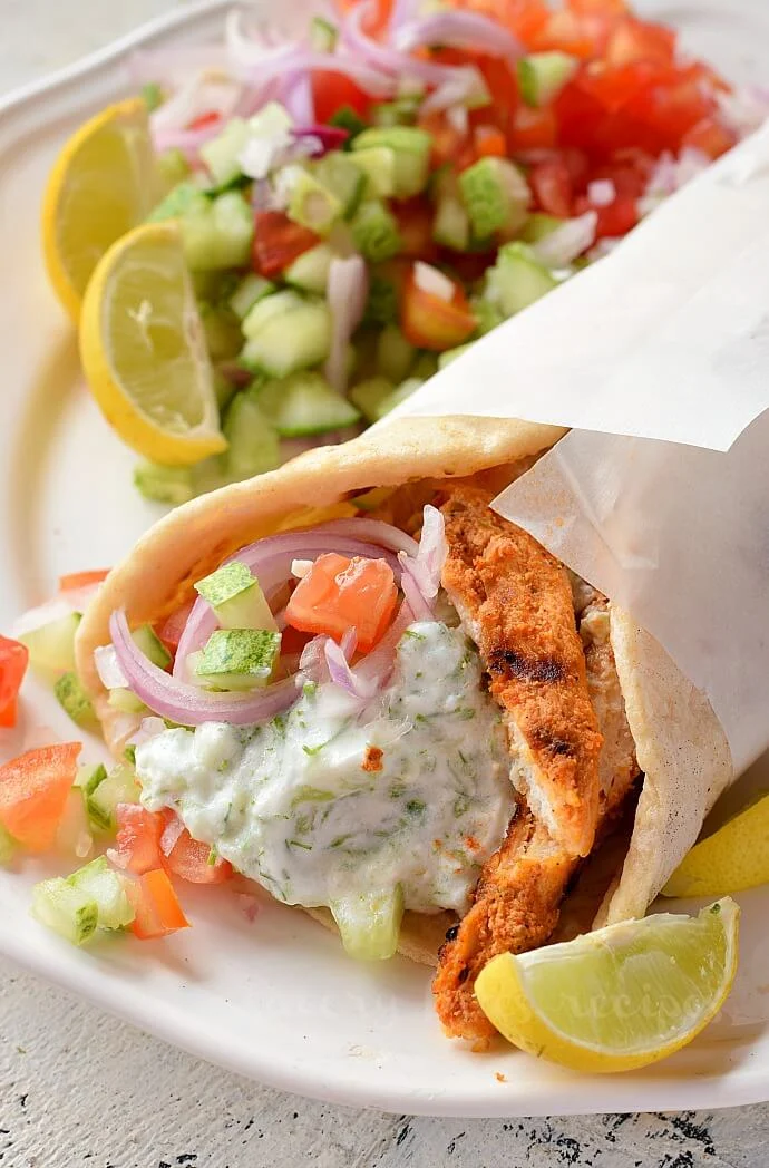 a white plate with easy chicken gyro with salad and homemade tzatziki