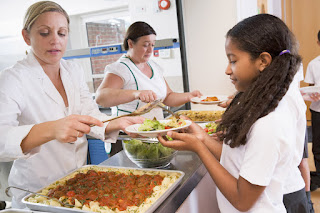 students being served lunch in cafeteria line