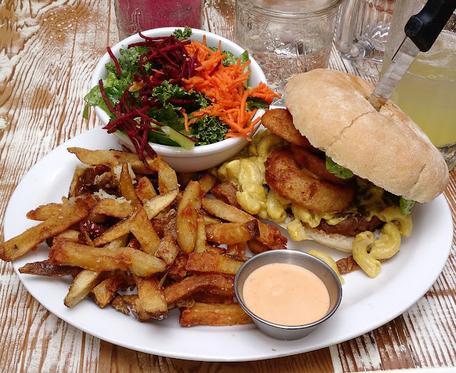 Vegan mac'n'cheese burger with onion rings, fries, and salad