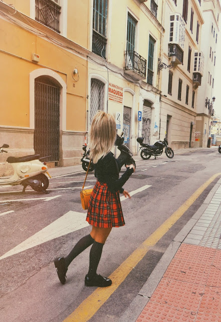 Alejandra Colomera vestida con jersey azul, falda roja cuadros escoceses, tirantes en color gris, calcetas gris y zapatos estilo colegial negro