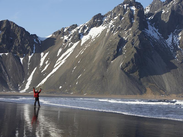 iceland mountain range with man in water below
