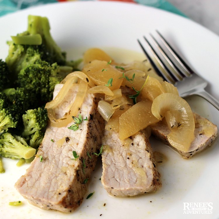 Three slices of Pork Loin Filet with Apples and Onions by Renee's Kitchen Adventures on a white plate with fork and broccoli on the side
