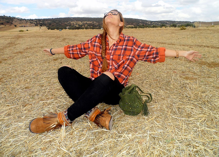 Camisa de cuadros con vaqueros rotos, botas boho, sombrero y bolso
