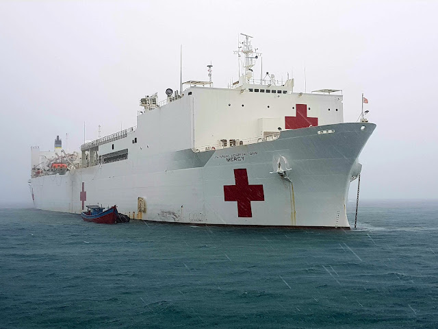 A large Navy ship is docked in the ocean.