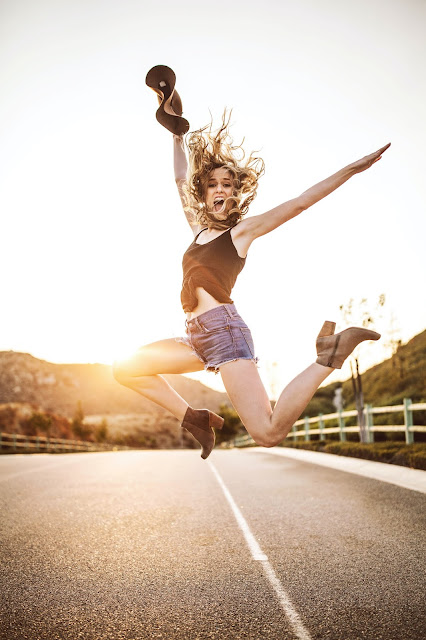 A woman jumping representing whether profound happiness is a barrier to self development