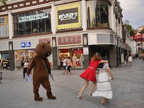 young woman jumping away from a person in a bear suit in Ganzhou