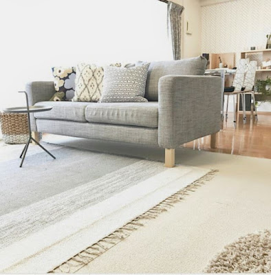 Gray sofa with throw pillows and round small coffee table on rugs