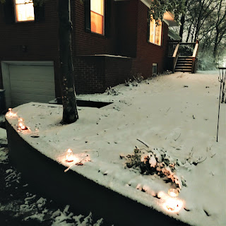 Candles in mason jars on a wall in the snow