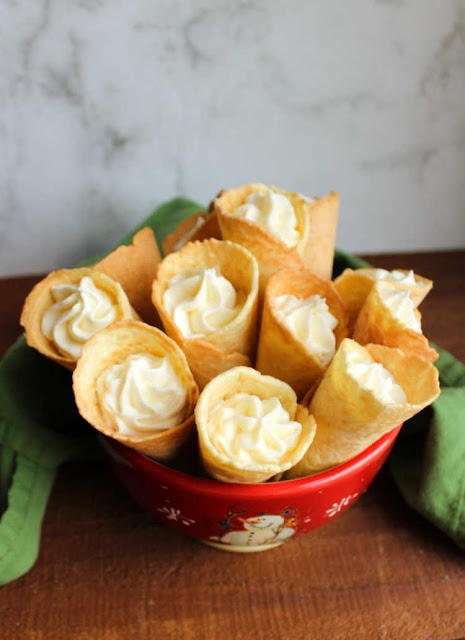 If you are looking for a fun new cookie to add to your recipe box, krumkake definitely fit the bill. They are crunchy and delicious plain and even better when filled with whipped cream or frosting. The iron is pretty and can also be used for making homemade pizelles or stroopwaffles as well! bowl of frosting filled krumkake cookies