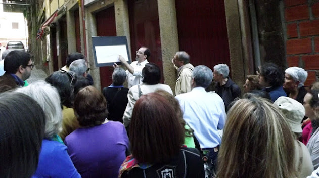 Homem com cartaz na mão mostrando para várias pessoas onde se encontrava um albergue para peregrinos no Porto Medieval