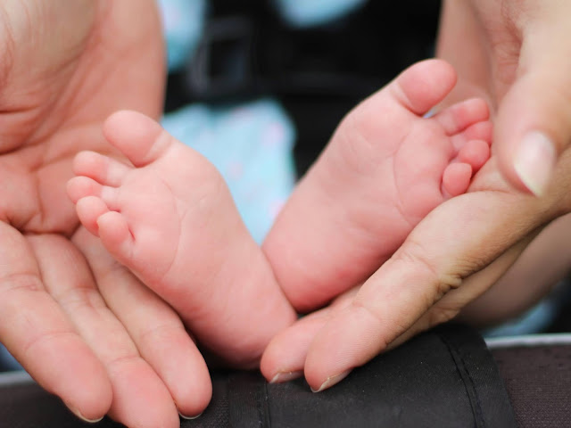 a woman holding a newborn baby's feet in her hands