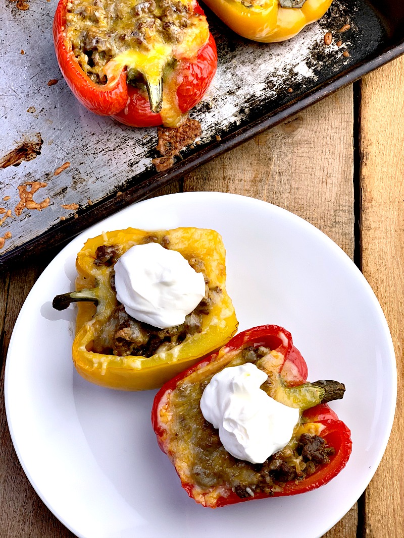 Overhead photo of Taco Stuffed Peppers on a white plate with more on a sheet pan in the background,