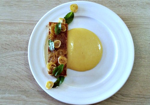 Un bizcocho recubierto de mermelada de naranja sobre una salsa de naranja