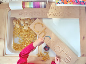 wooden name board with pasta and beads filling the letters