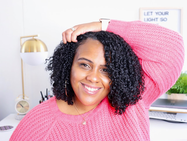 Girl with naturally curly hair smiling arm behind head