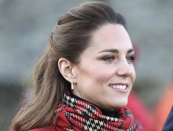 Kate Middleton wore a tartan pleated skirt from Emilia Wickstead, yellow gold hoops from Spells of Love. Alexander McQueen red coat. Grace Han bag