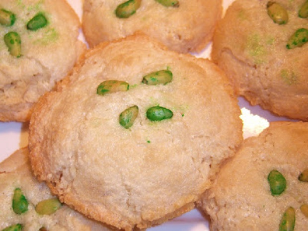 this is a platter of almond paste cookies with pine nuts on top tinted green