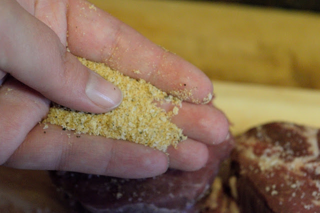 Two fillets on a cutting board with steak seasoning being sprinkled on them.  