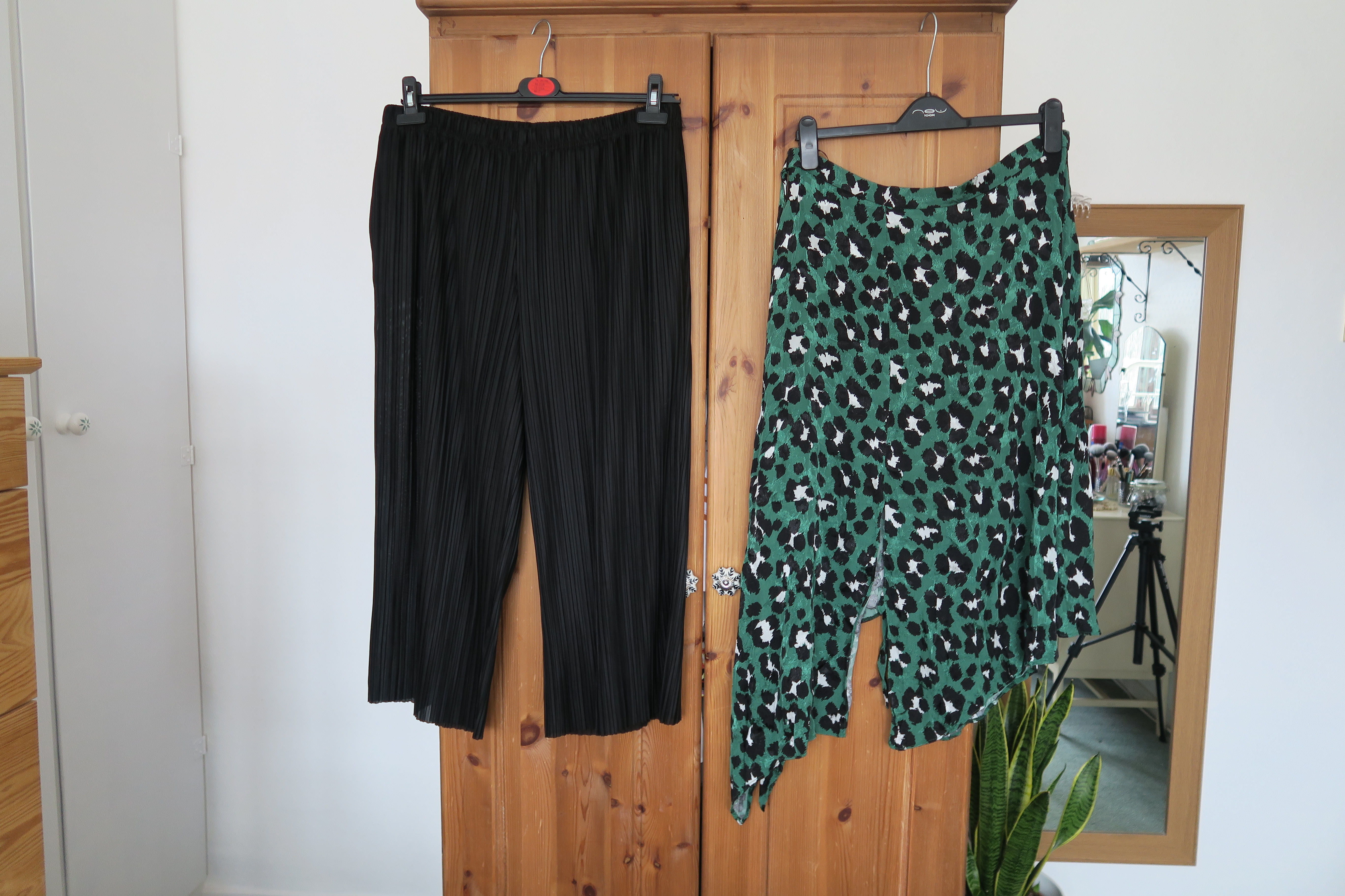 a pair of black culottes and a green skirt hanging from a wardrobe door