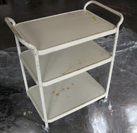 Cream colored hospital cart with rust stains.