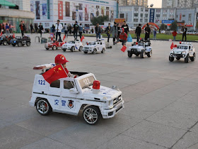 boy driving an electric kiddie car with a PRC flag in Mudanjiang, China