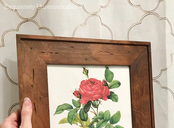 Framed rose print held up to a shower curtain in the bathroom