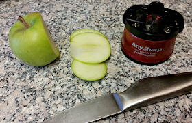 The AnySharp knife sharpener, a knife and a chopped apple.