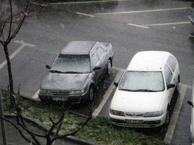 A cair neve sobre os carros no parque atrás da nossa casa em Janeiro de 2006. A neve a cair sobre os carros estacionados por trás da nossa casa em Portugal.