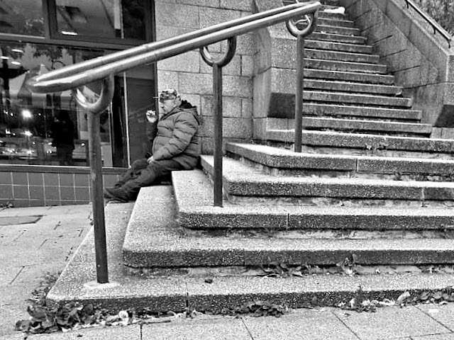 Black & white photo of man smoking on steps