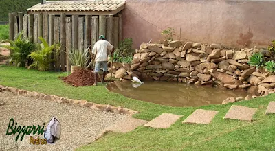 Construção do lago com as paredes de pedra onde vamos colocar a bica d'água de madeira para o monjolo de madeira funcionar. Na foto fazendo o buraco onde vamos colocar o pau para instalar o eixo de madeira do monjolo.