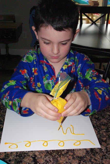 child using bag to pipe paint onto paper