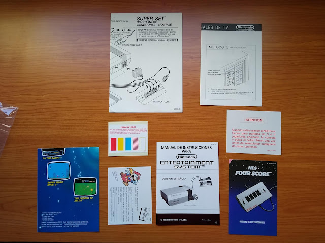 Instrucciones de la NES, Poster de SPACO, Tarjeta del Club Nintendo de SPACO, pegatinas de colores del Four Score, Instrucciones del Four Score y advertencia de Four Score